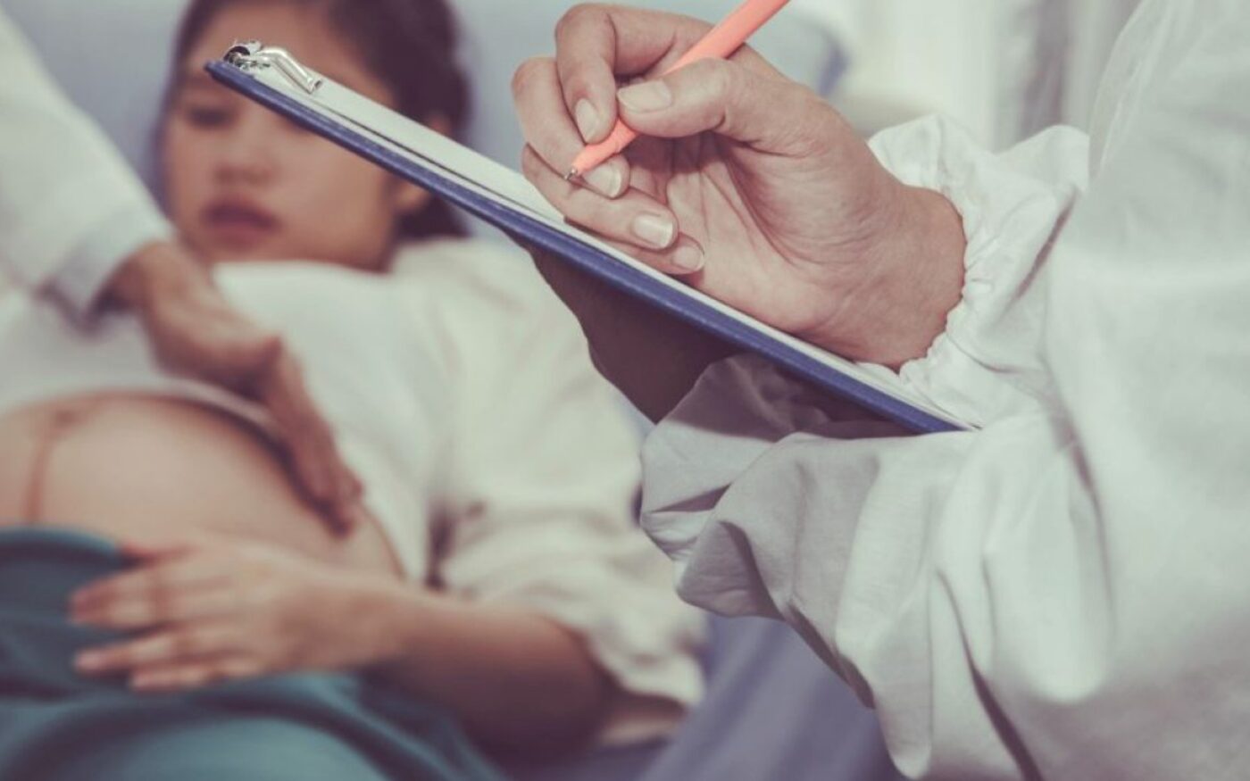 Zorgverlener maakt aantekeningen tijdens een consult bij een zwangere vrouw